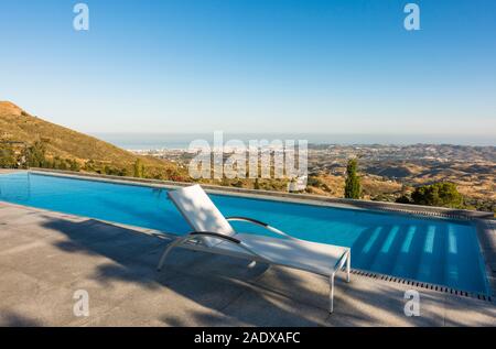 Piscine à débordement avec chaise longue et vue de la côte méditerranéenne, Malaga, Espagne. Banque D'Images