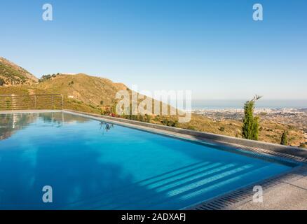 Piscine à débordement avec chaise longue et vue de la côte méditerranéenne, Malaga, Espagne. Banque D'Images