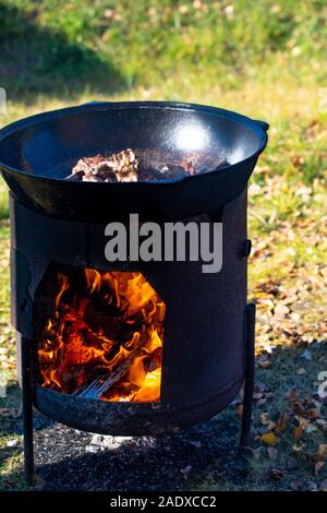 Faire cuire des morceaux de viande sur le feu dans un grand chaudron. La viande cuit dans un grand chaudron. L'horreur d'un végétarien. Les gros morceaux de viande sont cuits sur le Banque D'Images