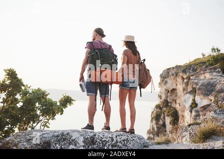 Deux mâles et de tourisme femme avec des sacs à dos sont au haut de la falaise et d'apprécier le lever du soleil. Voyages montagnes et la côte, de la liberté et active Banque D'Images