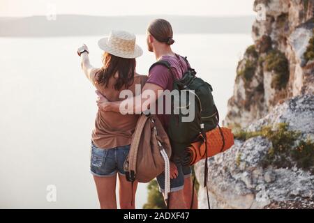 Deux mâles et de tourisme femme avec des sacs à dos sont au haut de la falaise et d'apprécier le lever du soleil. Voyages montagnes et la côte, de la liberté et active Banque D'Images