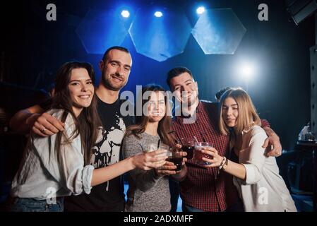 C'est si bon d'être de nouveau ensemble. Groupe de jeunes amis de sourire et de faire un toast à la discothèque Banque D'Images