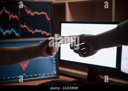 Vue de côté. Jour de salaire dans le bureau moderne avec des écrans et des graphiques sur eux Banque D'Images