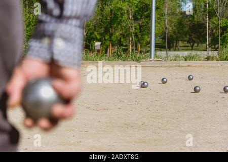 Les cadres prêts à jeter la boule de pétanque dans un parc de jeux à l'extérieur Banque D'Images