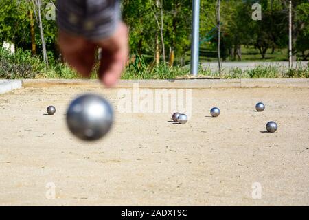 Les cadres prêts à jeter la boule de pétanque dans un parc de jeux à l'extérieur Banque D'Images