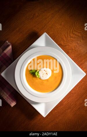 Soupe maison organique en blanc bol, dans des réglage sur table à manger en bois Banque D'Images