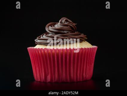 Cupcake à la vanille avec glaçage au chocolat à Nice, moule de papier sur fond rose Banque D'Images