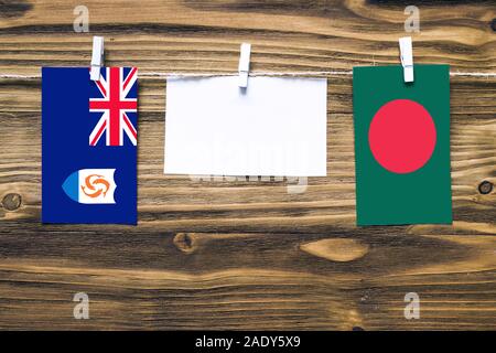 Drapeaux suspendus d'Anguilla et le Bangladesh attaché à corde avec pinces à linge avec de l'espace de copie sur papier blanc sur fond de bois.e diplomatique Banque D'Images