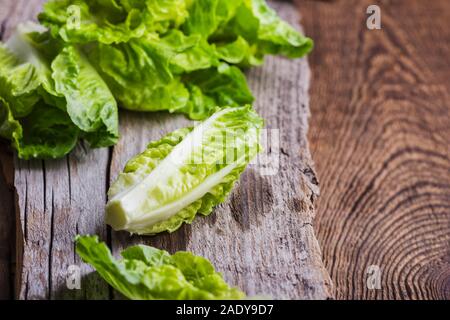 Laitue bébé frais sur planche de bois. Végétalien sain basé sur l'alimentation de l'usine table rustique en bois Banque D'Images