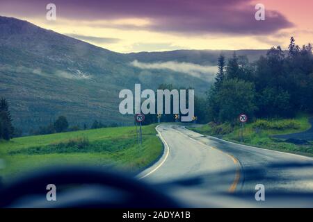 Conduire une voiture sur une route de montagne. La route entre les montagnes avec un ciel nuageux orageux. Paysage. La belle nature de la Norvège. Banque D'Images