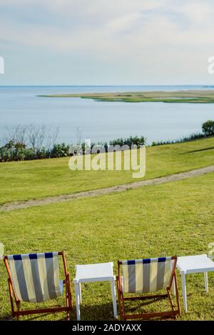 Chaise de plage vide sur prairie sur l'heure d'été. La lumière du soleil et la mer en arrière-plan. La ligne de côte Banque D'Images