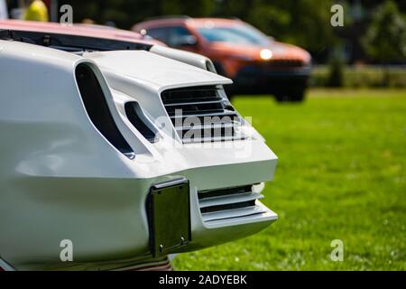 Classic American muscle blanc voiture rapide/avec des fonctionnalités, sur l'herbe de spectacle en plein air, à l'ouvrir le capot, voitures floues en arrière-plan Banque D'Images