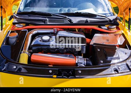 Sous le capot de la petite voiture jaune indiquant le réglage d'un moteur haute performance et la modification, rouge, argent, chrome et nettoyer les pièces en fibre de carbone Banque D'Images