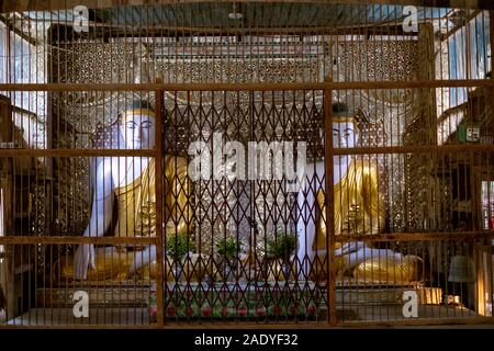 Deux statues du Bouddha assis dans un petit temple du village avec décoration ouvragée derrière une cage dorée, dans le nord-ouest de Myanmar (Birmanie) Banque D'Images