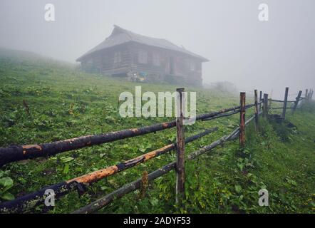 Paysage de montagne dans le brouillard. maison de montagne. Le vieux spooky maison sur la terre de nulle part. Maison en bois au milieu de la terre stérile. Sce Banque D'Images