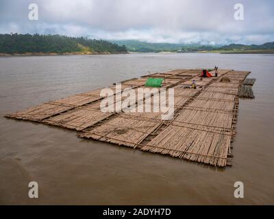 Faites de radeaux de bois d'exploitation forestière (avec un travailleur temporaire le logement dans les journaux) flotter dans la rivière Chindwin au bois d'yards dans le sud du Myanmar (Birmanie) Banque D'Images