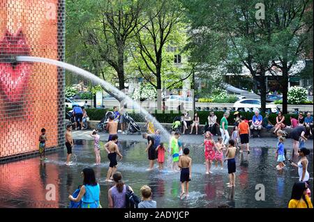 Chicago, Illinois, USA. Un jeu pour enfants se rafraîchir à la Fontaine de la Couronne à Chicago's Millennium Park sur une chaude journée d'été. Banque D'Images