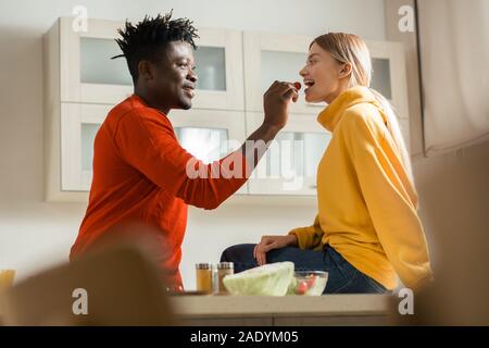 Genre jeune homme à nourrir ses smiling girlfriend avec tomate cerise Banque D'Images