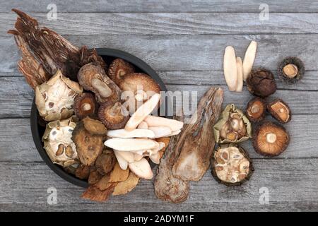 Herbes chinoises traditionnelles utilisées dans la médecine de fines herbes antique sur fond de bois rustique. Mise à plat. Banque D'Images