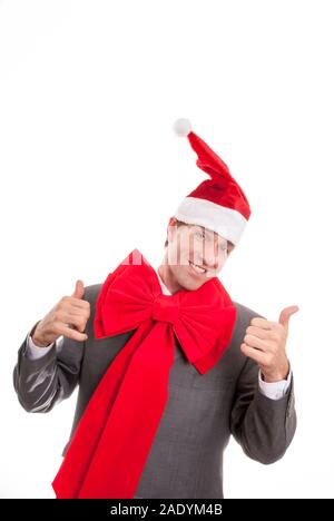 Smiling businessman wearing Santa hat and matching big bright Red bow vacances donnant deux pouces vers le haut sur fond blanc Banque D'Images