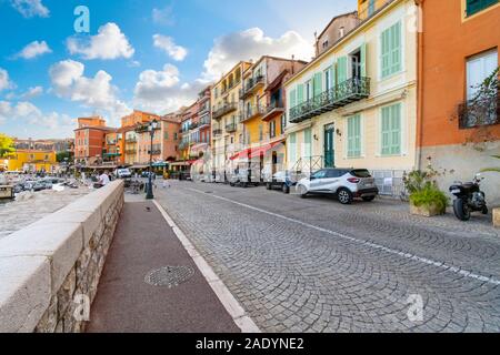 Les touristes à pied une rue pavée en face d'une rangée d'appartements colorés et cafés à Villefranche-sur-Mer, sur la côte méditerranéenne de la France Banque D'Images