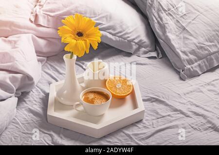 Plateau avec café, lait, orange et jaune dans un vase de fleurs. Banque D'Images