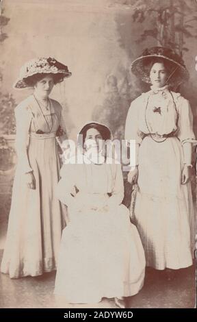 Vintage Début xxe siècle Carte postale photographique montrant trois jeunes femmes élégamment vêtu. Porter de beaux chapeaux. Banque D'Images