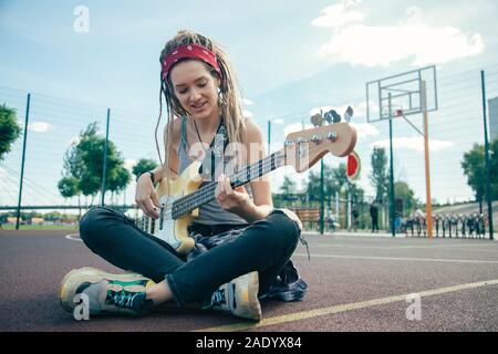 Jolie femme assise avec les jambes croisées et jouant de la guitare Banque D'Images