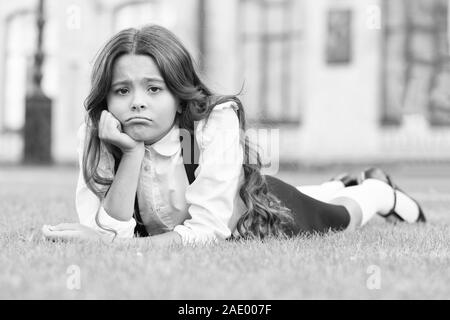 Sans un sourire triste. Triste lycéenne vous détendre sur l'herbe verte. Adorable petit enfant triste avec émotion sur le visage. Se sentir triste et malheureux. La tristesse et la dépression. Les problèmes à l'école. Banque D'Images