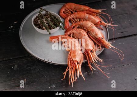 Grosses crevettes crues sur une table en bois sombre. Close-up. Les fruits de mer. Banque D'Images