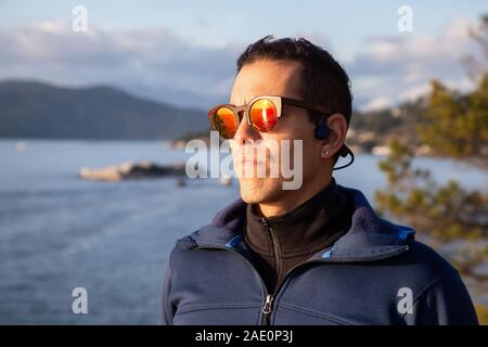 Portrait d'un homme à l'extérieur de l'Amérique latine d'aventure dans la nature lors d'un ciel nuageux et ensoleillé au coucher du soleil. Pris dans Lighthouse Park, Horseshoe Bay, Vancouver Ouest, C.-B., Banque D'Images