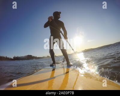Homme aventureux surfeur sur un paddle board est le surf dans l'océan lors d'un matin ensoleillé dans la saison d'automne. Prises à Long Beach, Tofino, Vancouver Island, Banque D'Images