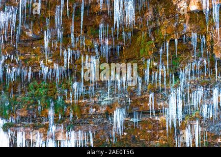 Les petits glaçons sur un versant couvert de mousse dans une forêt proche d'une cascade Banque D'Images