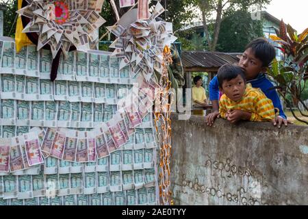 Deux jeunes garçons birmans stare lors d'un défilé d'offrandes pour les moines du village dans une cérémonie annuelle pour les honorer, dans le nord-ouest de Myanmar (Birmanie) Banque D'Images