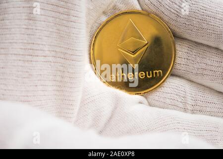 Homme en blanc girofle holding Ethereum coin entre les paumes de main. La monnaie numérique, bloc marché chaîne Banque D'Images