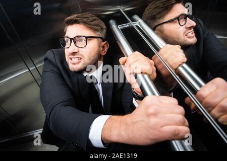 Portrait de l'homme effrayé en costume avec la claustrophobie dans l'élévateur Banque D'Images