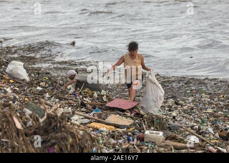 Manille, Philippines - Le 23 août 2017 : une femme la collecte des déchets en plastique dans un tas d'ordures dans la mer Banque D'Images