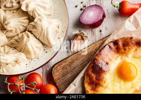 Vue de dessus de délicieux khinkali près d'Adjarie khachapuri sur table en bois Banque D'Images