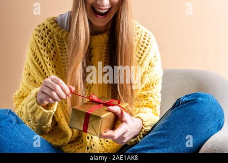 Portrait de femme en pull jaune holding gift box alors qu'il était assis dans un fauteuil sur rond Banque D'Images