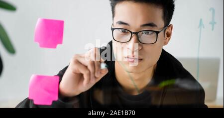 Vue panoramique shot of asian seo manager dans la peinture sur verre verres flèche Banque D'Images