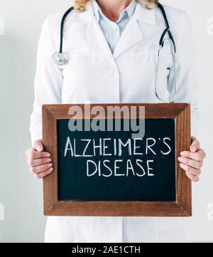 Portrait d'un médecin en blouse blanche tenant conseil avec lettrage en bois de la maladie d'Alzheimer Banque D'Images