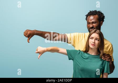 Déplut couple interracial showing Thumbs down isolé sur fond bleu Banque D'Images