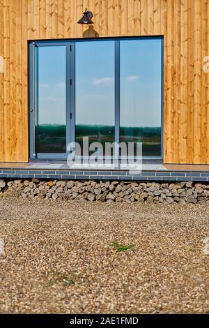 Façade en bois de la maison en bois. En bois jaune bordés. Fenêtres panoramiques. Vue parfait reflet dans une fenêtre de ciel bleu. Le concept d'éco-architecture Banque D'Images