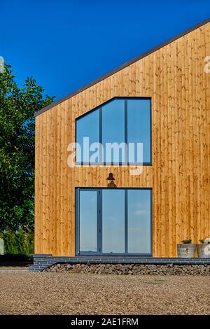 Façade en bois de la maison en bois. En bois jaune bordés. Fenêtres panoramiques. Vue parfait reflet dans une fenêtre de ciel bleu. Le concept d'éco-architecture Banque D'Images