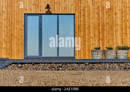 Façade en bois de la maison en bois. En bois jaune bordés. Fenêtres panoramiques. Vue parfait reflet dans une fenêtre de ciel bleu. Le concept d'éco-architecture Banque D'Images