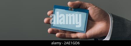 Portrait d'homme tenant un insigne isolé sur gray, vue panoramique tourné Banque D'Images