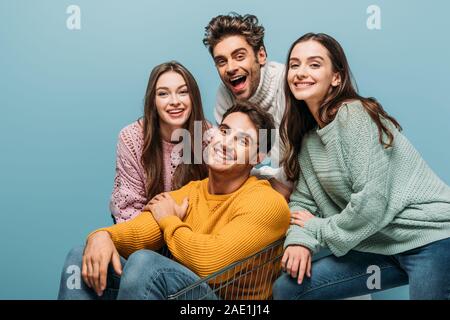 Smiling friends having fun avec panier, isolé sur bleu Banque D'Images