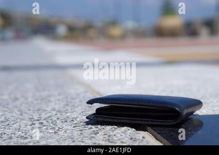 Etui en cuir noir perdu gros plan avec de l'argent déposer sur le trottoir, perdu de l'argent concept Banque D'Images