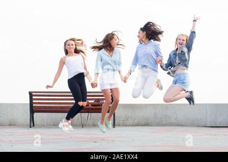 Quatre belles copines joyeux fou sauter et s'amuser dans le parc. Le bonheur, la joie, l'amitié, l'émotion concept Banque D'Images