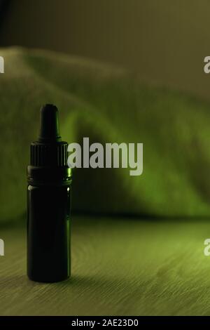 Seul 10 ml flacon en verre noir sur blanc rétroéclairé de table en bois avec feu vert Banque D'Images